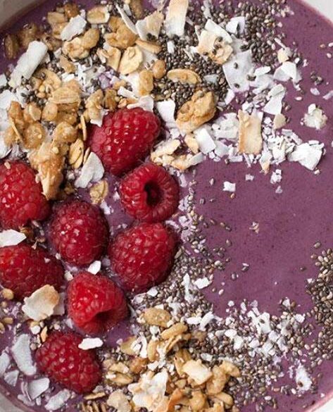 acai berry breakfast bowl, topped with seeds and fresh raspberries